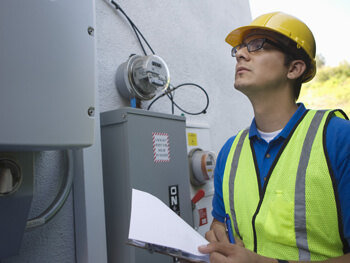 Electrician wearing safety hat and vest inspecting electrical equipment