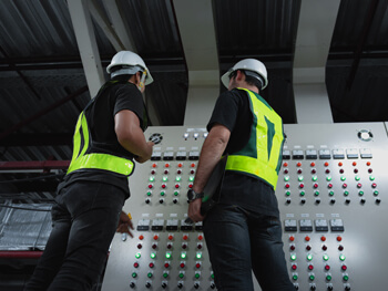 Two electricians discussing an industrial electrical project on-site